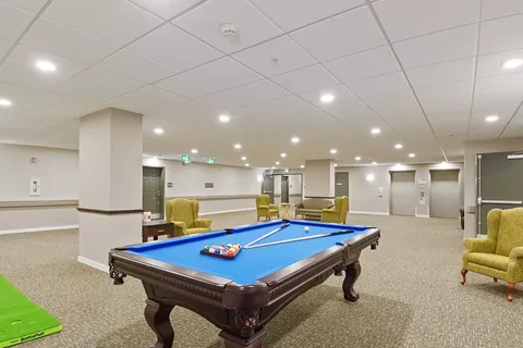 Room with a blue pool table, seating and overhead lights