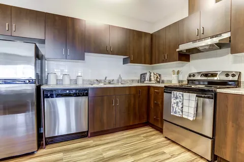 Kitchen with dark wood cupboards, a refrigerator, stove and dishwasher