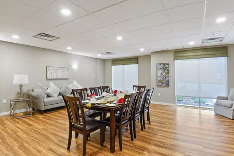Dining table set with cups, plates and red napkins beside upholstered seating