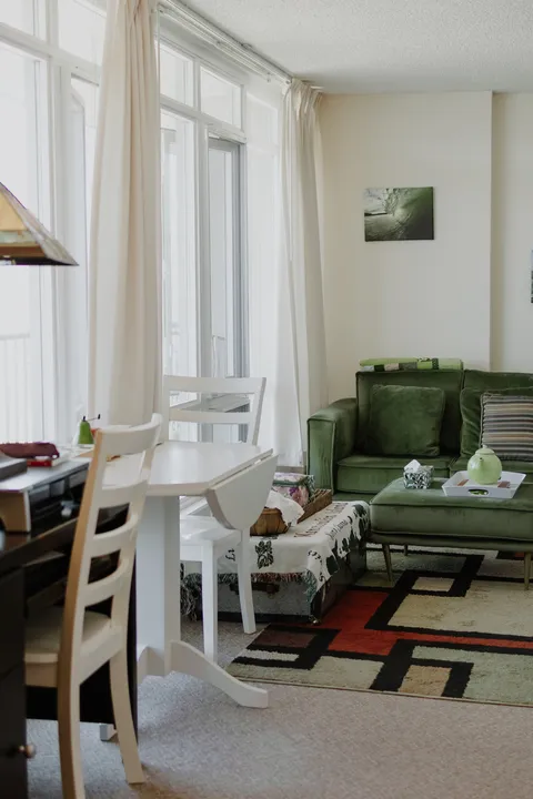 Sitting area with a green armchair beside large windows