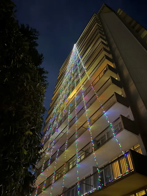 Residence tower at night with strings of coloured lights along balconies