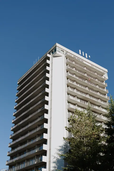 Residence tower with rows of balconies beneath a clear blue sky