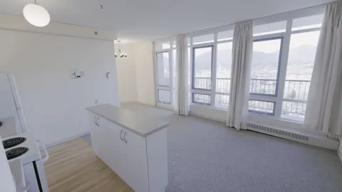 Empty room with a kitchenette and windows opening onto a balcony
