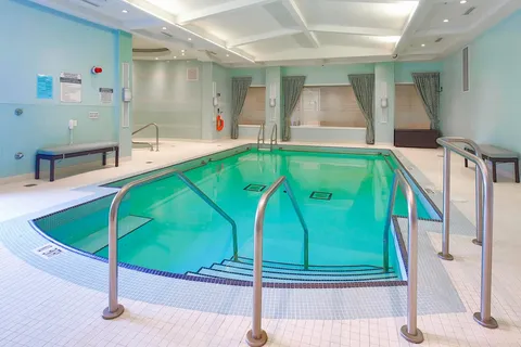 Indoor pool with handrails and a tiled deck