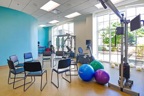 Fitness room with exercise equipment beside large windows