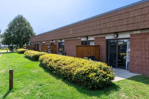 Brick residence wing beside a lawn and trimmed shrubs.