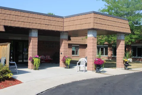 Covered brick entrance with flower planters and outdoor chairs.