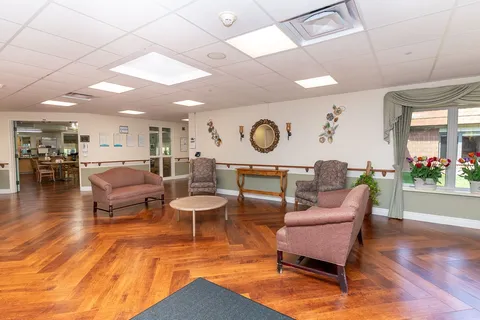Lobby with armchairs, tables and polished wooden flooring.