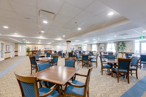 Dining room with wooden tables, blue upholstered chairs and large windows