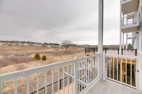 White balcony railings beside the residence overlooking brush and distant houses