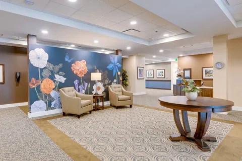 Seating area with beige armchairs, a floral mural and a round wooden table