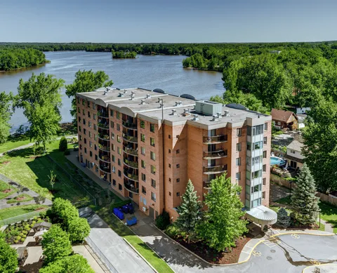 Aerial view of a brick residence beside a river and trees
