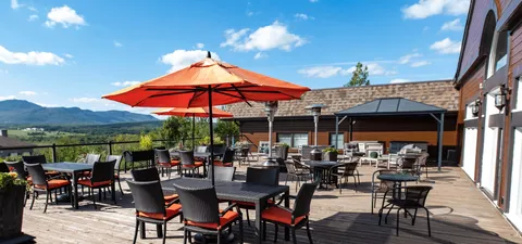 Terrace tables beneath red umbrellas overlooking nearby hills