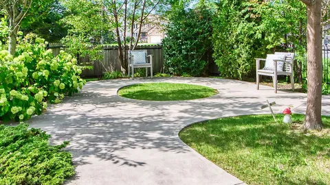 Paved garden path with shrubs and outdoor chairs.
