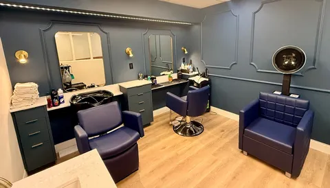 Salon with styling chairs, mirrors and hair-washing station.