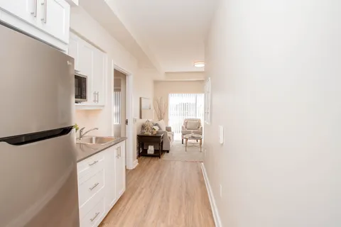 Kitchenette beside a narrow passage leading to seating and windows
