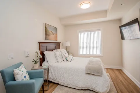 Bedroom with a wooden bed, a teal armchair and a television