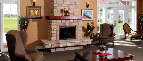 Lounge with armchairs and a stone fireplace.
