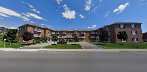 Brick residence exterior with landscaped lawns and a central driveway.