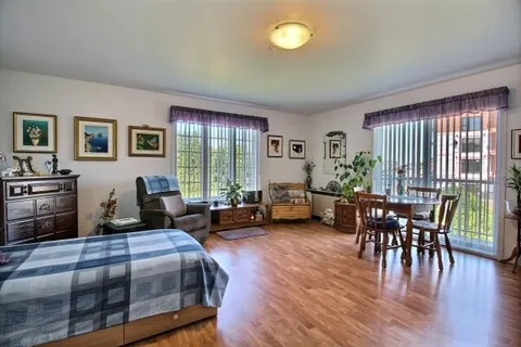 Studio suite with a bed, sitting area, dining table and large windows.