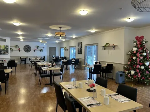 Dining room with set tables, chairs, plants and a seasonal tree.