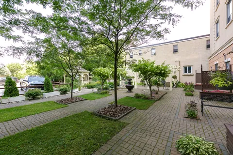 Paved courtyard with trees, a lawn and a tiered fountain