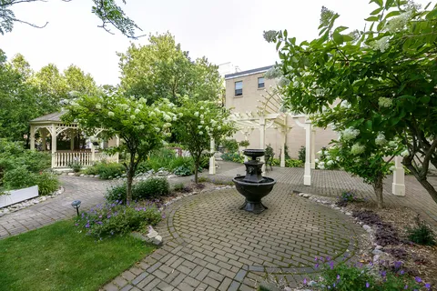 Garden with a tiered fountain, paved paths, flowering shrubs and a gazebo