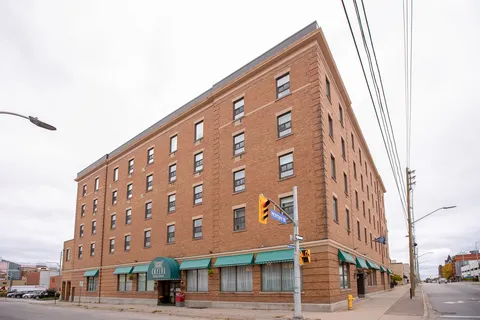 Corner view of a brick residence building with green awnings