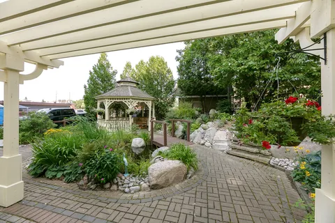 Garden path beneath a pergola beside a gazebo, stone steps and flowers