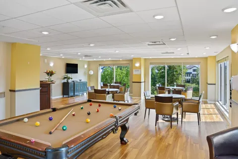 Room with a billiards table and seating beside large windows