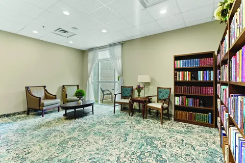 Armchairs, tables and bookshelves beside a curtained window
