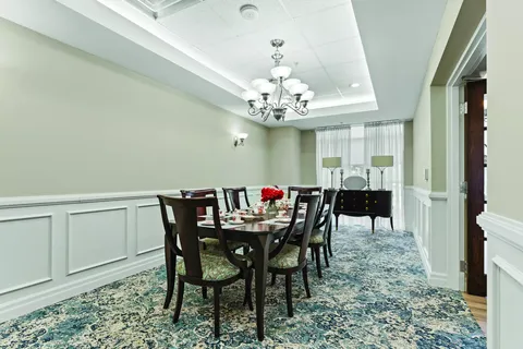 Dining table beneath a chandelier beside a sideboard