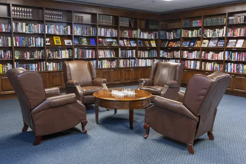 Library with bookshelves and reclining chairs around a table.