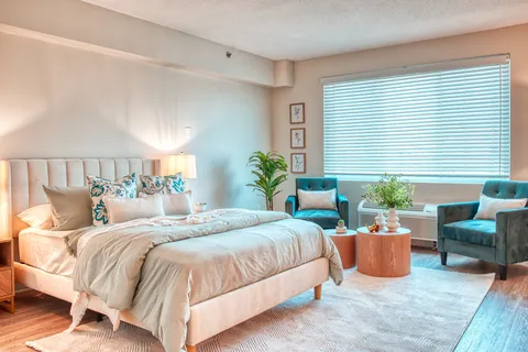 Bedroom with a bed, bedside tables and seating by a window.