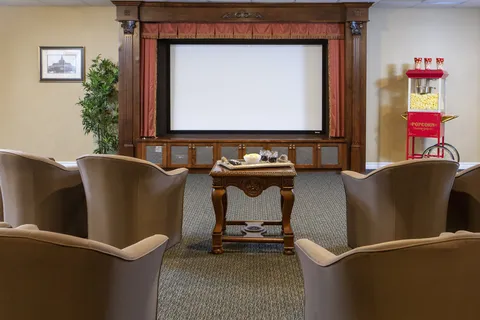 Screening room with lounge chairs, a screen and popcorn machine.