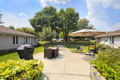 Courtyard with a lawn, seating, a path, plants and a patio umbrella.