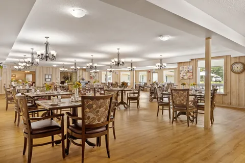 Dining room with set tables, wooden chairs, columns and chandeliers.