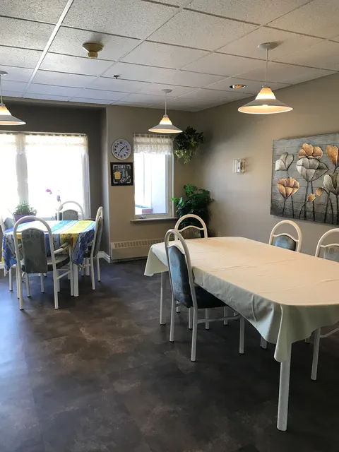 Small dining area with round tables and chairs beside windows.