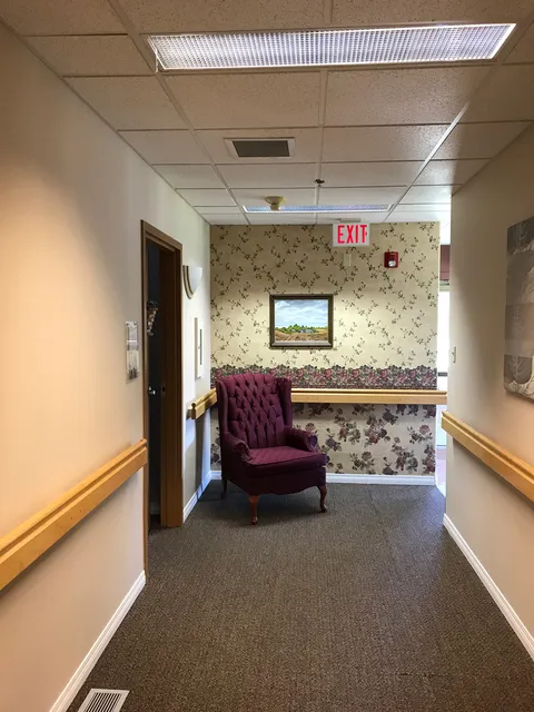 Corridor with safety rails and an upholstered chair at the far end.