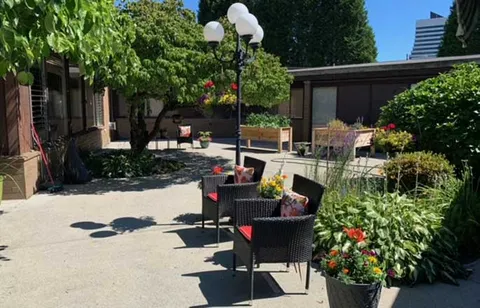 Courtyard with chairs, flowering planters and a lamp post