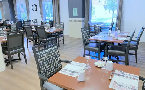 Dining room with tables, chairs and broad windows.
