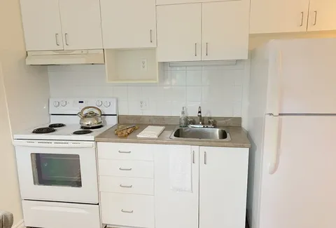 Kitchen with a stove, refrigerator and white cabinets.