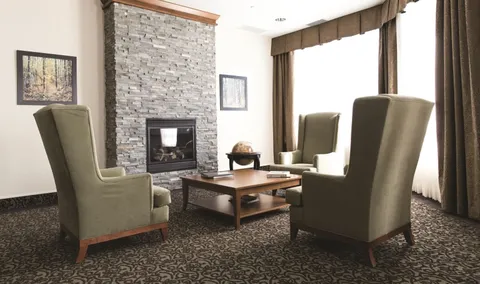 Sitting area with upholstered chairs and a stone fireplace.