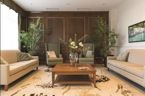 Lounge with sofas, armchairs, plants and a wood-panelled wall.