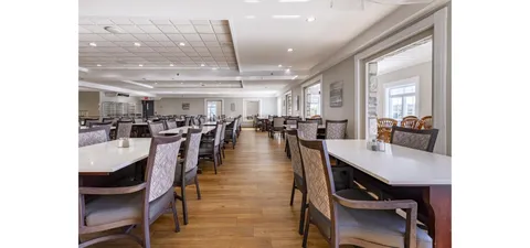 Dining room with rows of white tables and patterned upholstered chairs