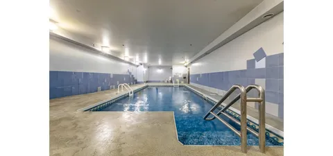 Indoor swimming pool with blue wall tiles and metal handrails