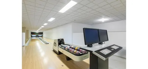 Bowling lanes with a ball return and two dark scoring screens