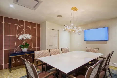 Meeting room with a rectangular table, chairs and wall television.