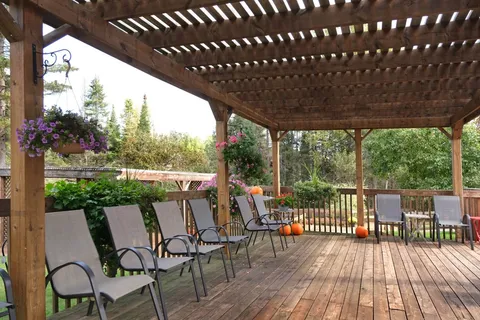 Outdoor chairs beneath a pergola on a wooden deck