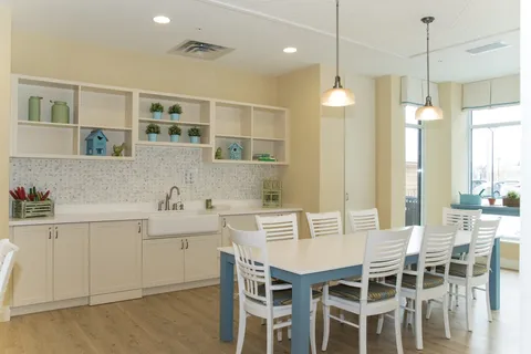 Bright room with a large table, white chairs, cabinets and a sink